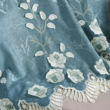 Sinivalkoinen verho kirjailluilla kukilla