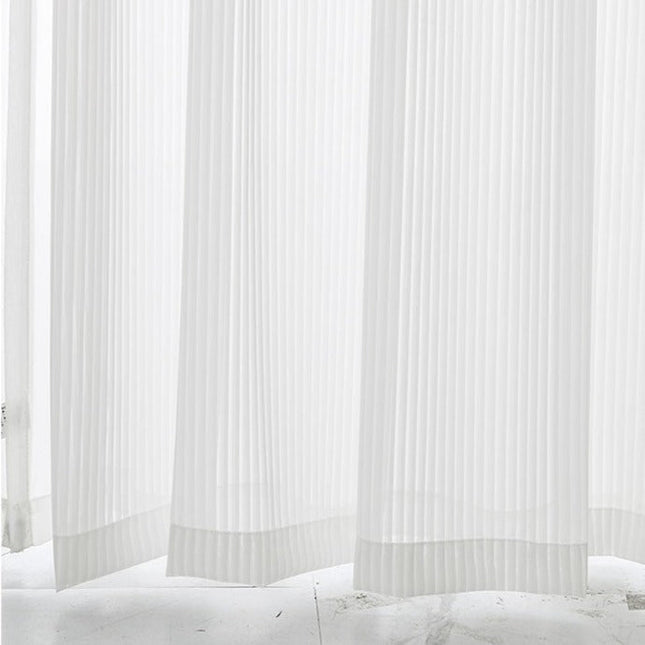 Valkoinen pystysuoraan laskostettu valkoverho