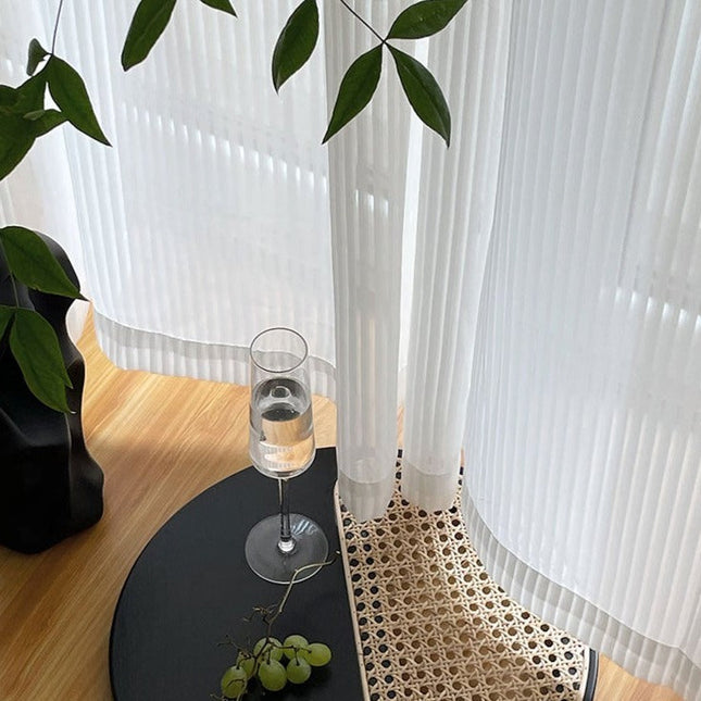 Valkoinen pystysuoraan laskostettu valkoverho