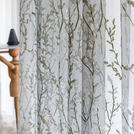 Läpikuultava verho kirjaillulla oksakuviolla