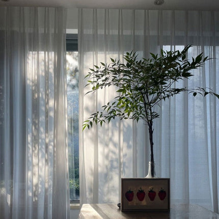 Valkoinen pystysuoraan laskostettu valkoverho