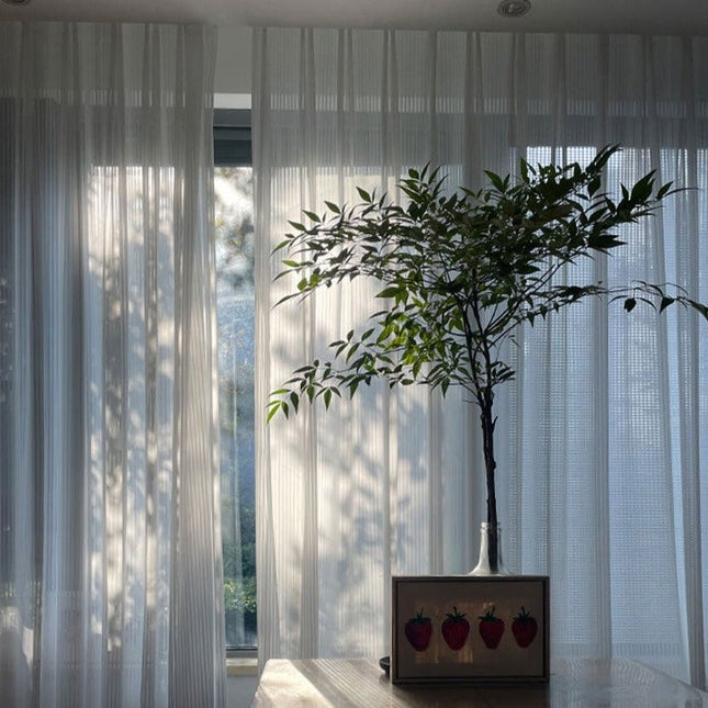 Valkoinen pystysuoraan laskostettu valkoverho