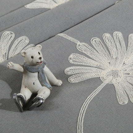 Harmaa verho brodeeratuilla päivänkakkaroilla