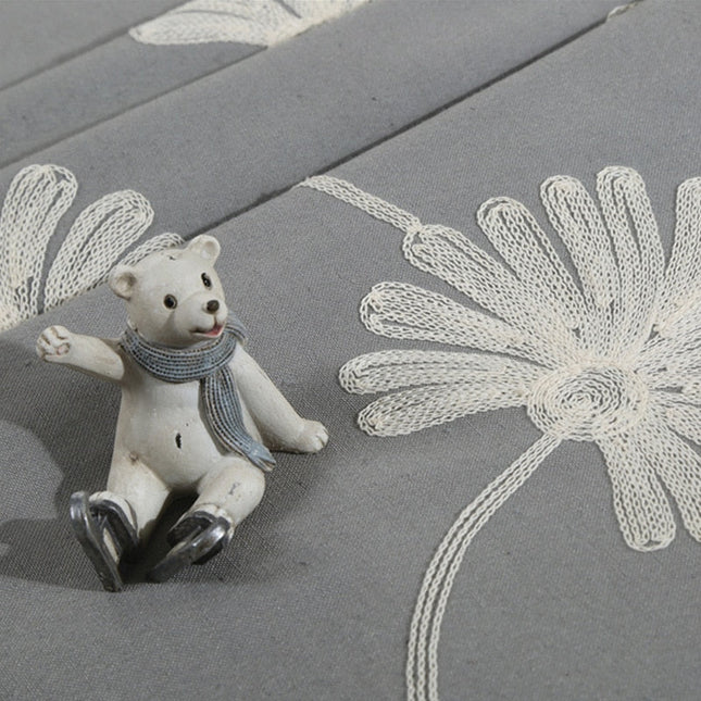 Harmaa verho brodeeratuilla päivänkakkaroilla