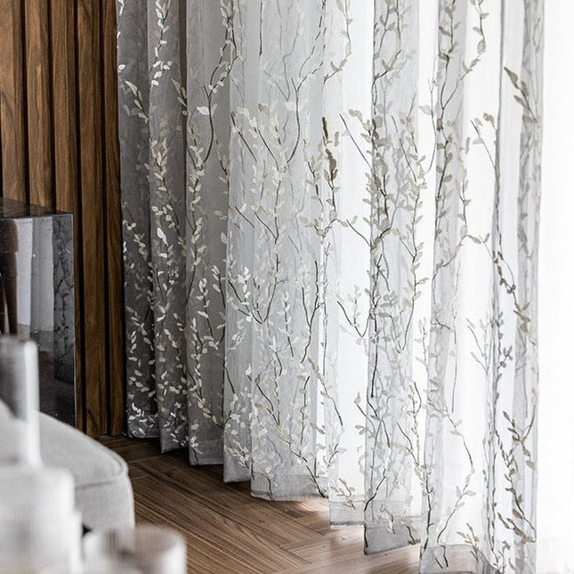Läpikuultava verho kirjaillulla oksakuviolla