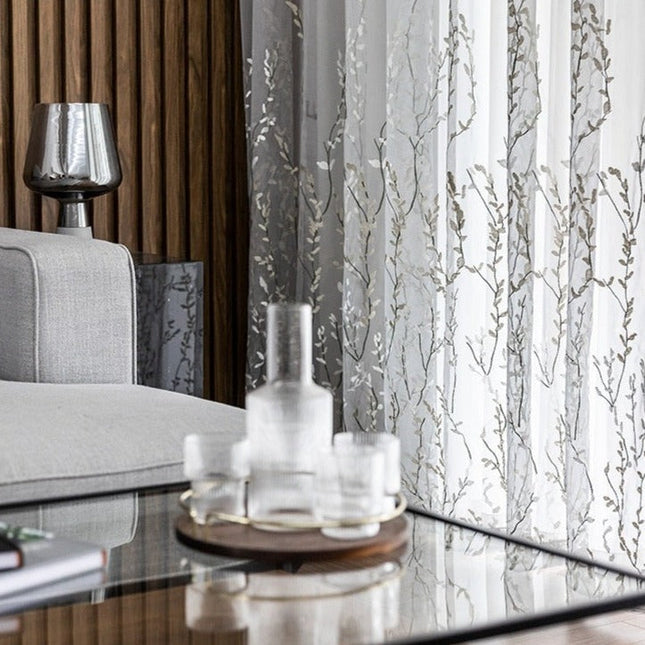 Läpikuultava verho kirjaillulla oksakuviolla