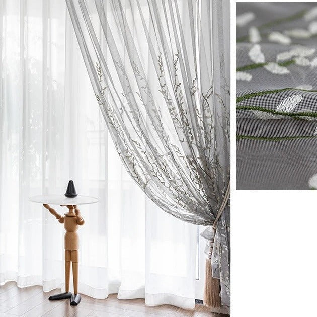 Läpikuultava verho kirjaillulla oksakuviolla