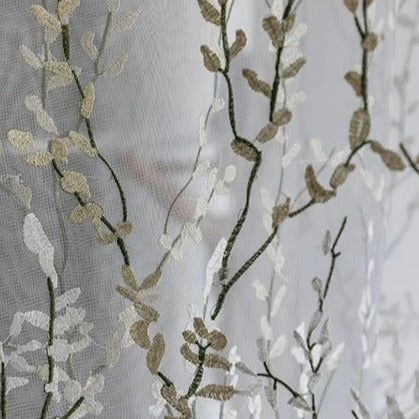 Läpikuultava verho kirjaillulla oksakuviolla