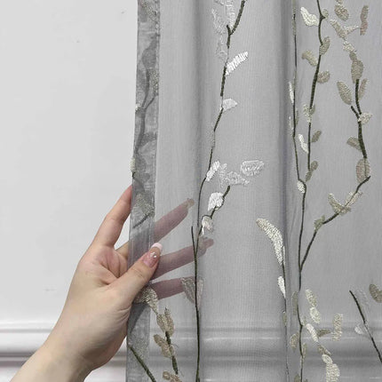 Läpikuultava verho kirjaillulla oksakuviolla